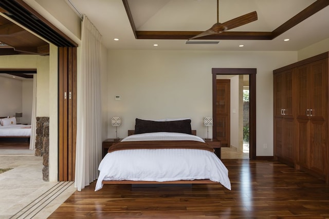 bedroom featuring a tray ceiling, dark hardwood / wood-style floors, and ceiling fan