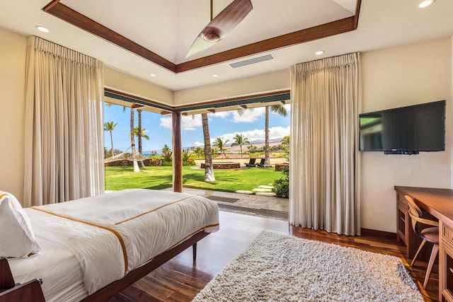 bedroom featuring access to exterior, dark hardwood / wood-style floors, and a raised ceiling