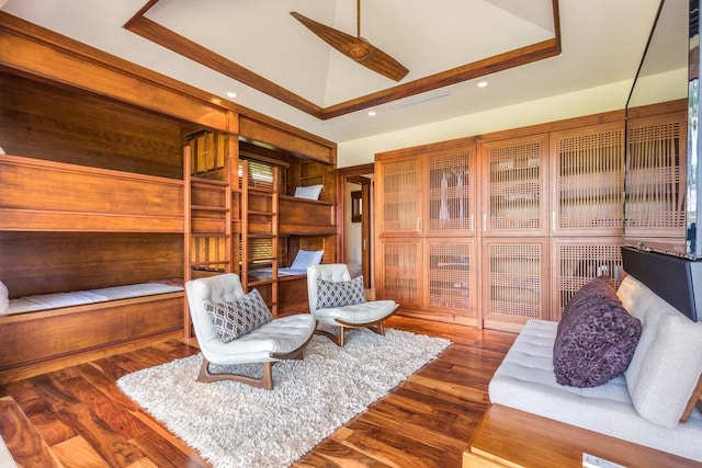 sitting room featuring dark wood-type flooring, ceiling fan, and a tray ceiling