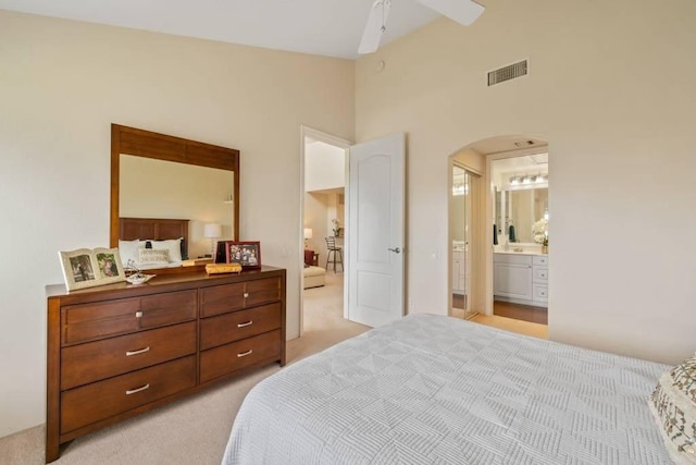 bedroom with ensuite bathroom, light carpet, ceiling fan, and high vaulted ceiling