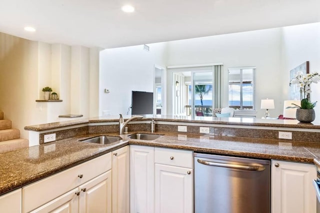 kitchen with white cabinetry, stainless steel dishwasher, sink, and dark stone countertops