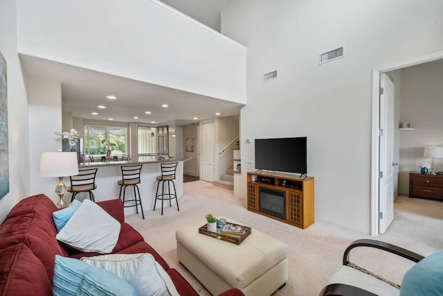 carpeted living room with a towering ceiling