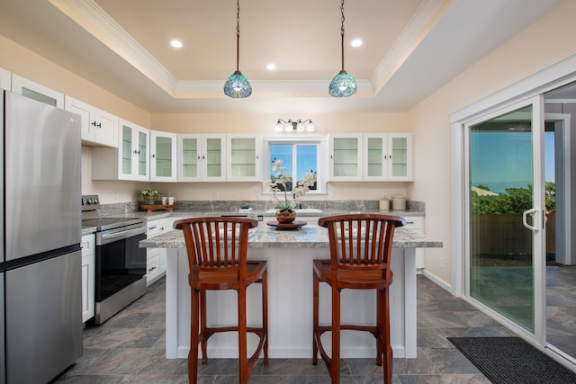 kitchen featuring appliances with stainless steel finishes, white cabinets, hanging light fixtures, a center island, and a tray ceiling