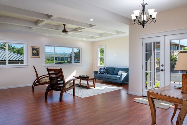 living room with dark wood-type flooring, coffered ceiling, ceiling fan with notable chandelier, french doors, and beamed ceiling