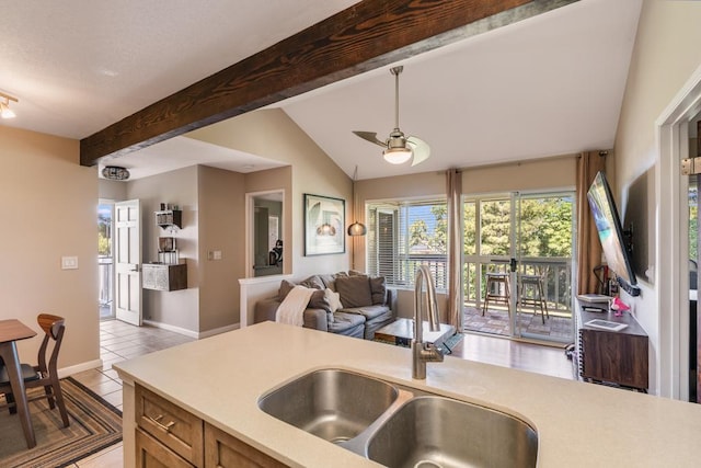 kitchen featuring sink, light tile patterned floors, vaulted ceiling with beams, and ceiling fan