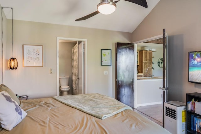 bedroom featuring ceiling fan, ensuite bath, sink, and vaulted ceiling