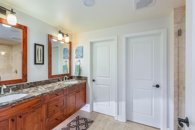 bathroom with a shower with door, vanity, and tile patterned floors