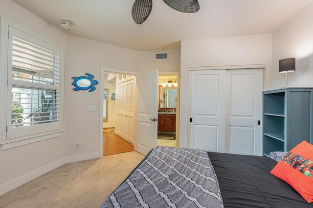 bedroom with light colored carpet, ensuite bath, and a closet