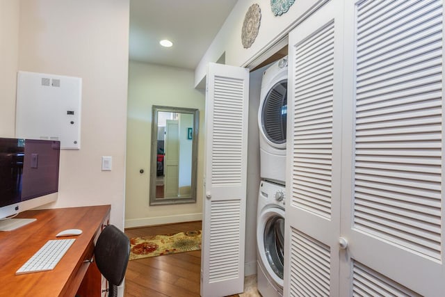 laundry room featuring hardwood / wood-style flooring and stacked washer / drying machine