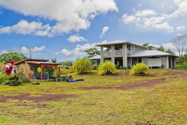 back of property featuring metal roof, a lawn, and a balcony