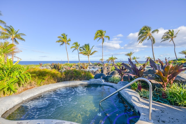 view of pool with an in ground hot tub and a water view