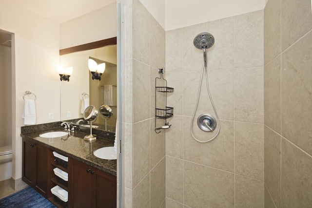 bathroom featuring vanity, a tile shower, and toilet