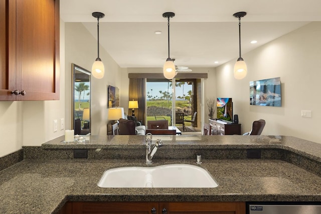 kitchen featuring sink, stainless steel dishwasher, hanging light fixtures, and dark stone counters