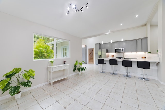 kitchen featuring gray cabinets, appliances with stainless steel finishes, backsplash, a kitchen bar, and kitchen peninsula