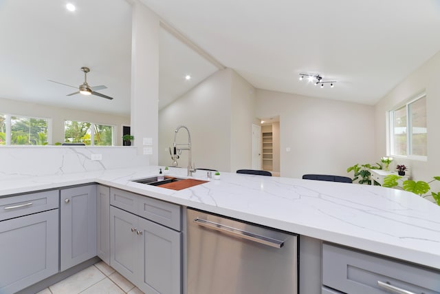 kitchen with light stone counters, stainless steel dishwasher, kitchen peninsula, and sink