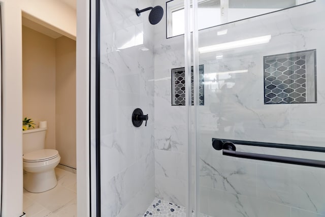 bathroom featuring a shower with shower door and toilet