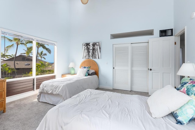 bedroom featuring light carpet, visible vents, a closet, and a towering ceiling