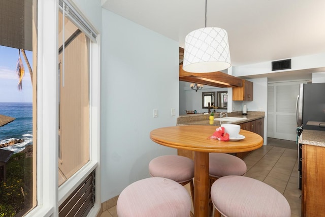 dining room featuring a water view, visible vents, a notable chandelier, and light tile patterned flooring