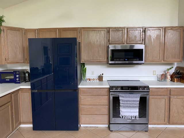 kitchen featuring light tile patterned flooring, lofted ceiling, and stainless steel appliances