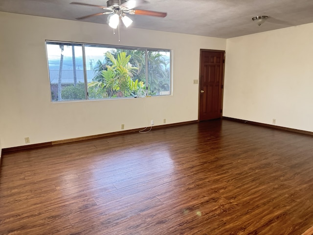 unfurnished room with ceiling fan, baseboards, and dark wood-type flooring