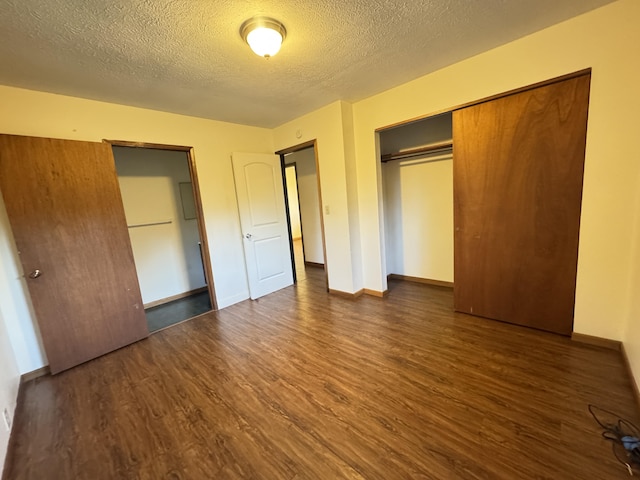 unfurnished bedroom with a textured ceiling, dark wood-style flooring, a closet, and baseboards