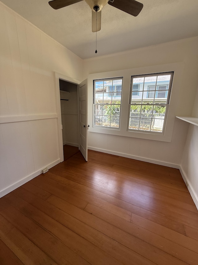 unfurnished bedroom with multiple windows, ceiling fan, hardwood / wood-style floors, and a textured ceiling