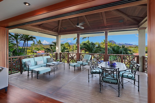 wooden terrace featuring a ceiling fan, an outdoor hangout area, a gazebo, a mountain view, and outdoor dining space