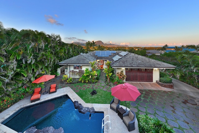 pool at dusk with a yard and an outdoor pool