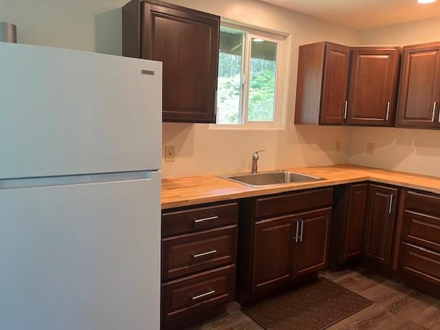 kitchen with white fridge, sink, dark hardwood / wood-style floors, and dark brown cabinets