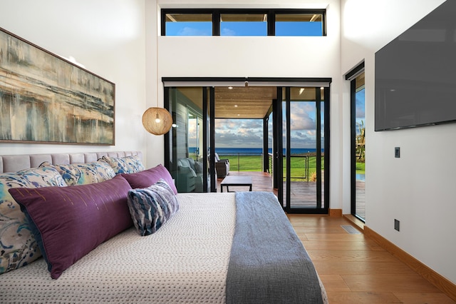 bedroom with a high ceiling, access to exterior, and light hardwood / wood-style floors