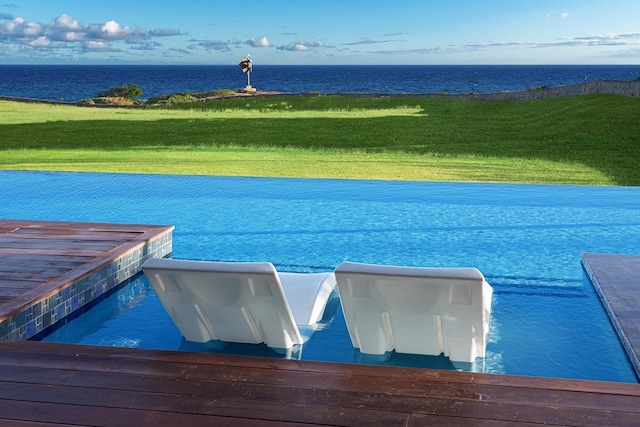 view of swimming pool featuring a water view and a lawn