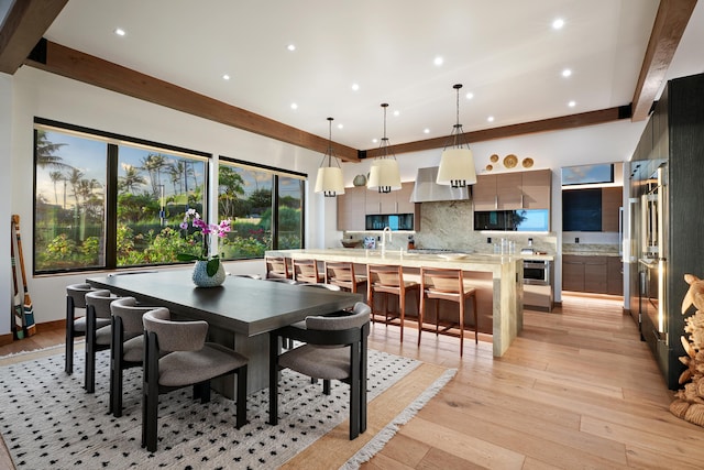 dining room with beam ceiling and light wood-type flooring