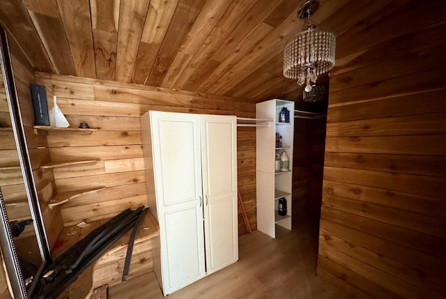 hall featuring light wood-style floors, wooden ceiling, a notable chandelier, and wooden walls