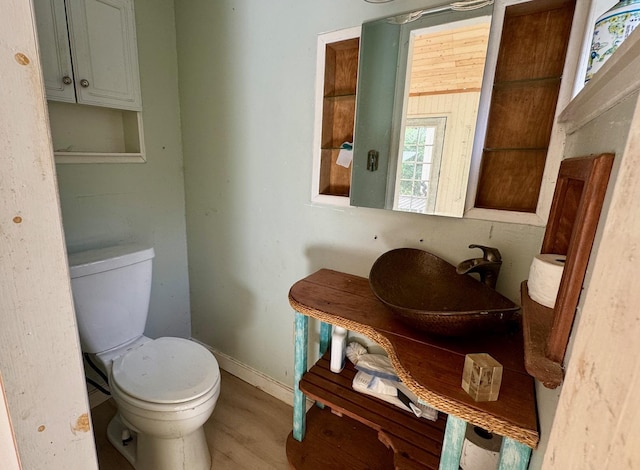 bathroom with toilet, baseboards, wood finished floors, and vanity