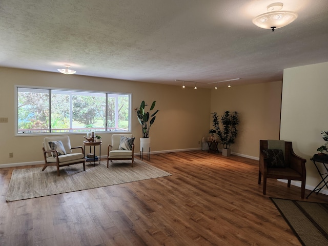 living area with wood-type flooring, rail lighting, and a textured ceiling