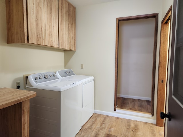 laundry area featuring cabinets, separate washer and dryer, and light hardwood / wood-style floors