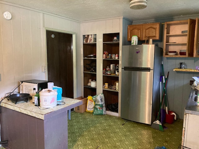 kitchen featuring stainless steel refrigerator and a textured ceiling