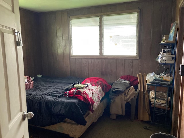 carpeted bedroom featuring multiple windows and wooden walls