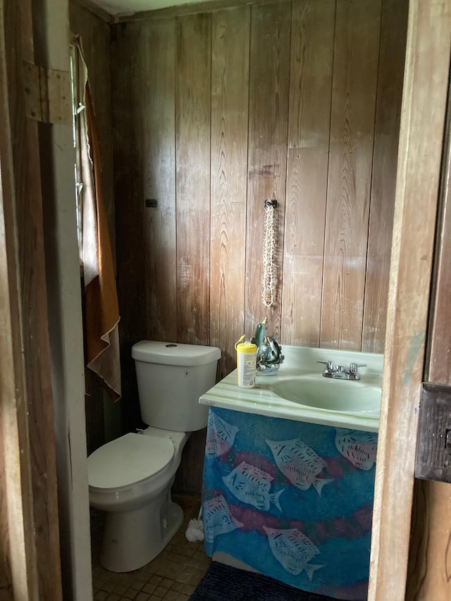 bathroom with vanity, wooden walls, tile patterned floors, and toilet