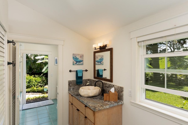 bathroom with tile patterned floors, vanity, and vaulted ceiling