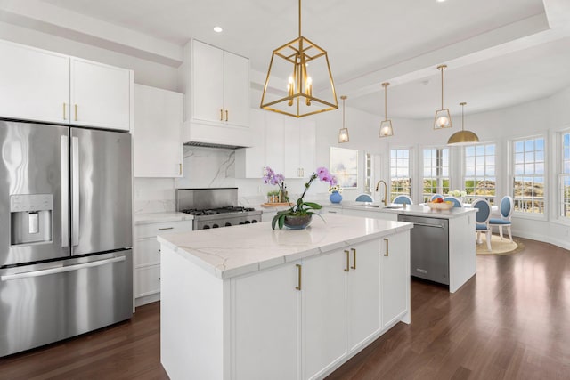 kitchen with white cabinetry, a center island, pendant lighting, stainless steel appliances, and light stone countertops