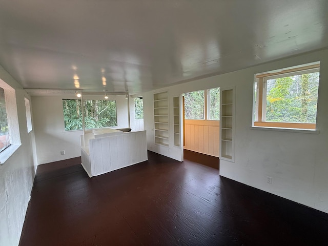 unfurnished living room with built in shelves and dark wood-type flooring