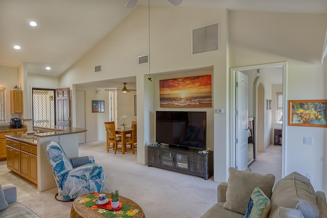 living room with ceiling fan, high vaulted ceiling, and light colored carpet