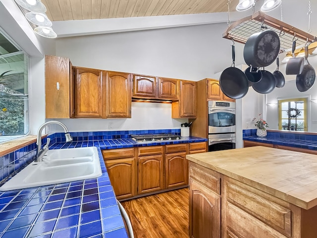 kitchen with sink, wood ceiling, beam ceiling, stainless steel appliances, and tile counters