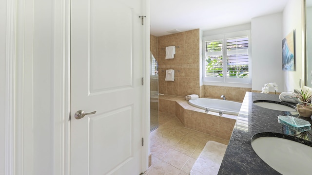 bathroom featuring double vanity, tile patterned floors, a garden tub, walk in shower, and a sink