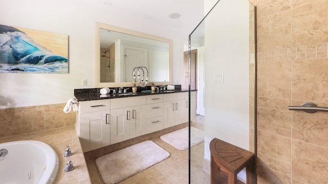 bathroom with double vanity, a tub with jets, a sink, and tile patterned floors