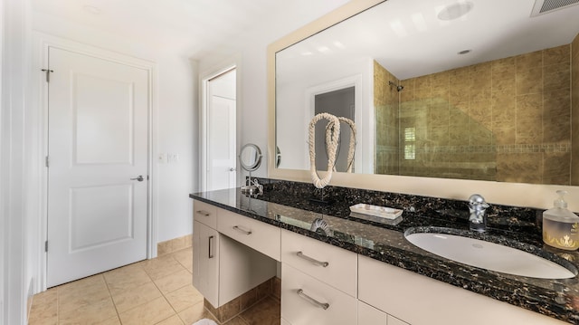 full bath featuring double vanity, visible vents, a sink, tile patterned flooring, and tiled shower