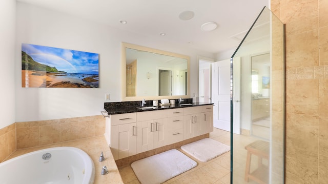 bathroom with a sink, double vanity, a tub with jets, and tile patterned flooring