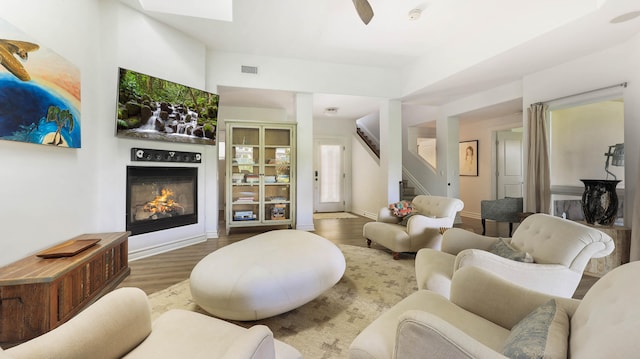 living area with wood finished floors, visible vents, baseboards, stairway, and a glass covered fireplace