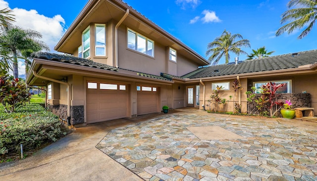 view of front of home featuring a garage, stone siding, a tile roof, and stucco siding